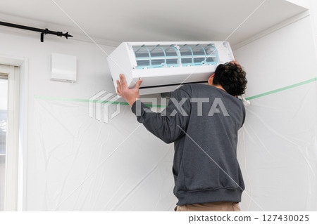A worker installing an air conditioner A worker installing an air conditioner 127430025
