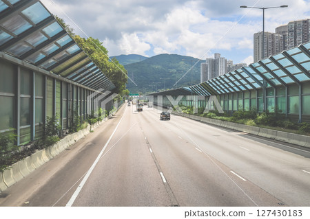 June 7 2025 Urban Highway with Cars Surrounded by Green Sound Barriers June 7 2025 Urban Highway with Cars Surrounded by Green Sound Barriers 127430183