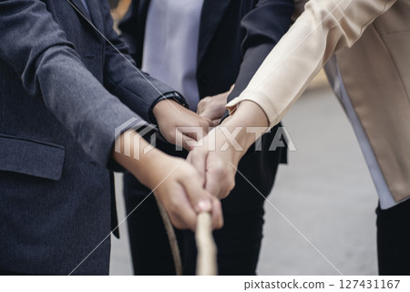 Tug of war Group of business people Hands pulling rope symbol team unified teamwork Partnership Concept. Businesswoman Team holding hands together partnership leader teamwork. diversity competition 127431167