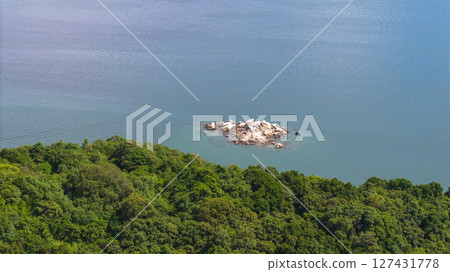 View of Forested Island Surrounded by Coastal City and Mountains 127431778