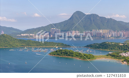 June 7 2025 Scenic Coastal View with Lush Greenery and Urban Buildings 127431810