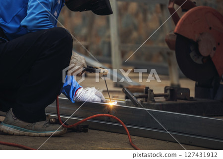 Construction Worker hands using Welding machinery iron metal sparking. Men hands wear protective glove Hot flame metal work cutting fire iron workshop. Locksmith use Welding machine cut metal process 127431912