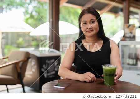 Mature Asian woman sitting in coffee shop 127432221