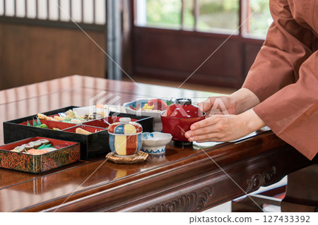 The hands of a female staff member serving food in a ryokan, guest room, or private room 127433392