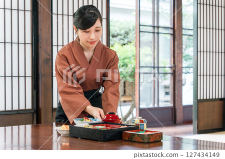 A waitress serving food to the guest rooms of an inn, a ryokan staff member 127434149