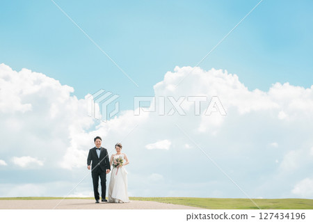 Bride and groom walking on a road with blue sky, wedding, bridal, wedding dress image Bride and groom walking on a road with blue sky, wedding, bridal, wedding dress image 127434196
