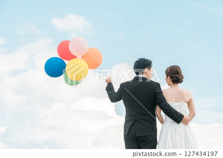 Back view of a bride and groom holding balloons (wedding, wedding ceremony, bridal, photo wedding) Back view of a bride and groom holding balloons (wedding, wedding ceremony, bridal, photo wedding) 127434197
