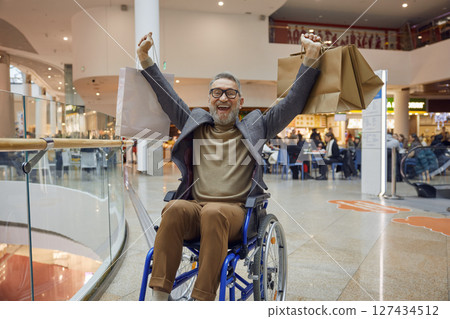 Happy smiling elderly man with disabilities in the wheelchair enjoying time in the shopping mall 127434512