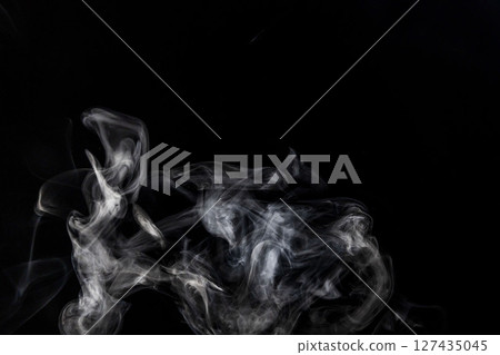Steam floating in front of a black background Steam floating in front of a black background 127435045