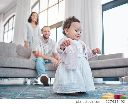 Baby, family and love with a girl learning or walking in the living room of her home with parents watching. Kids, floor and walk with a daughter taking her first steps with mom and dad in the house 127435492