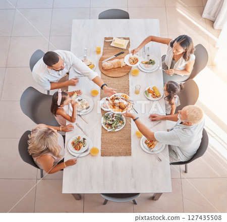 Family, lunch and food at the table with big family bonding, sharing and eating together at the dining table. Meal, top view and family home with a mother, father and grandparents and kids eat Family, lunch and food at the table with big family bonding, sharing and eating together at the dining table. Meal, top view and family home with a mother, father and grandparents and kids eat 127435508