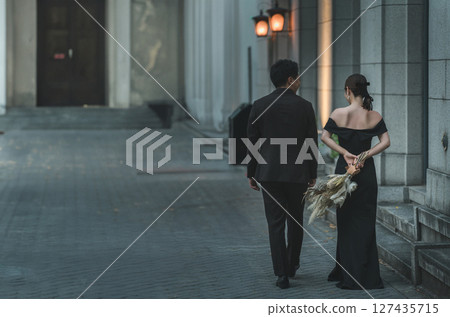 Date, man and woman in black dresses walking in the city at night, couple, bride and groom (dressed up) Date, man and woman in black dresses walking in the city at night, couple, bride and groom (dressed up) 127435715