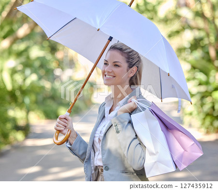 Sun, umbrella and woman with bags from shopping with smile and happy walking in park. Summer, nature and girl with shopping bags from luxury designer boutique and protection from uv rays in sunshine. 127435912