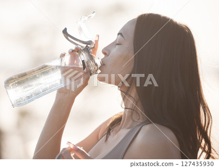 Drinking water, fitness and woman after running training, workout and exercise in nature. Wellness, health and morning female athlete with water bottle before runner sport and walking thirsty 127435930
