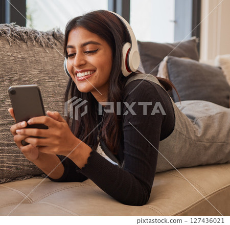 Woman, phone and headphones for listening to music online for happiness, calm and peace while streaming on audio app on home and living room sofa. Female watching video or movie on internet with 5g Woman, phone and headphones for listening to music online for happiness, calm and peace while streaming on audio app on home and living room sofa. Female watching video or movie on internet with 5g 127436021