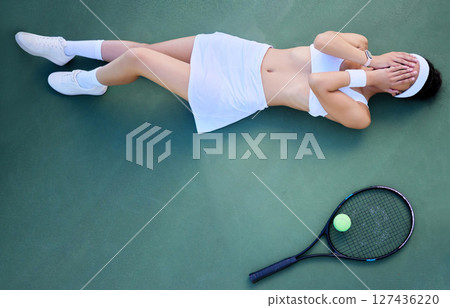 Top view, tennis court and tennis woman rest on ground with head in hands from sports fitness workout, game training and athletic workout. Tennis racket, tennis ball and tired athlete after exercise Top view, tennis court and tennis woman rest on ground with head in hands from sports fitness workout, game training and athletic workout. Tennis racket, tennis ball and tired athlete after exercise 127436220