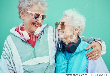 Happy, fashion and elderly friends hug in cool sunglasses, vintage jackets and modern headphones outdoors. Retro, wall background and senior women hugging with pride, freedom and smile in retirement Happy, fashion and elderly friends hug in cool sunglasses, vintage jackets and modern headphones outdoors. Retro, wall background and senior women hugging with pride, freedom and smile in retirement 127436411