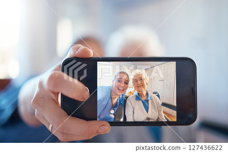 Phone, nurse and happy old woman take a selfie on screen after consulting with medical doctor. Photo, caregiver and healthy senior person in retirement take pictures for social media in nursing home 127436622