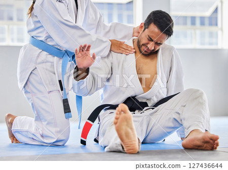 Karate, sports and neck injury pain of fighter on floor with surrender hand at professional athlete club. Accident, help and tournament of martial arts person in agony with muscle pain. 127436644