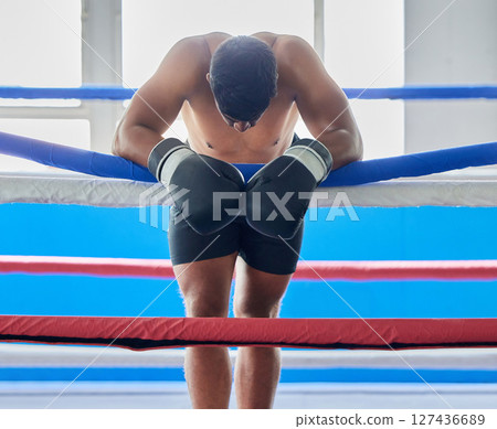Fitness, tired and sad boxer after a loss thinking about his defeat in a difficult battle in a boxing ring at a gym studio. Fatigue, loser and frustrated fighter feeling bad, depression and upset Fitness, tired and sad boxer after a loss thinking about his defeat in a difficult battle in a boxing ring at a gym studio. Fatigue, loser and frustrated fighter feeling bad, depression and upset 127436689