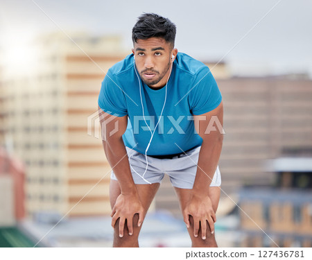 Man, tired and running in city for exercise, workout or training by blurred background, buildings and breathing. Runner, relax or rest to music, streaming or outdoor for fitness, health and wellness 127436781