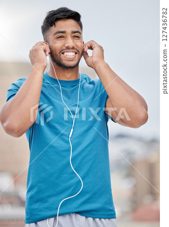 Man, music and earphones for city exercise for wellness, training and running by blurred background. Happy runner, listening and streaming on internet, web or app to relax at workout in urban metro 127436782