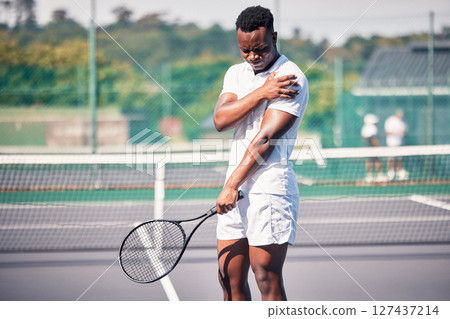 Sports, tennis and arm pain on court after training, game or match outdoors. Healthcare, tennis player and injured black man or athlete with muscle pain or inflammation after exercise or workout. 127437214