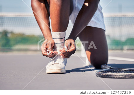 Sports, tennis and man tie shoes before game start, competition or fitness exercise on outdoor tennis court. Wellness health, ground and legs of African player prepare for workout, training or cardio Sports, tennis and man tie shoes before game start, competition or fitness exercise on outdoor tennis court. Wellness health, ground and legs of African player prepare for workout, training or cardio 127437239