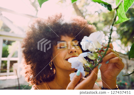 Woman, smell flowers and spring garden enviroment for plants wellness or sustainability. African person, green energy and smelling floral fragrance or gardening, ecology and happiness in nature 127437451