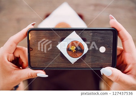 Smartphone photography, hands and coffee shop, cafe or restaurant for drink review on social media content marketing. Blog, ux and content creator holding phone screen of chocolate dessert from above Smartphone photography, hands and coffee shop, cafe or restaurant for drink review on social media content marketing. Blog, ux and content creator holding phone screen of chocolate dessert from above 127437536