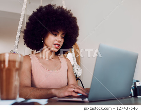 Black woman afro, laptop and designer working, studying or typing email in remote work at home. Stylish African American female freelancer busy on computer in design course or business research Black woman afro, laptop and designer working, studying or typing email in remote work at home. Stylish African American female freelancer busy on computer in design course or business research 127437540