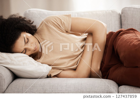 Pms, woman and stomach ache on a sofa from menstruation, period and cramps in a living room. Belly ache, black woman and pain from endometriosis, digestion or constipation problem on a couch at home Pms, woman and stomach ache on a sofa from menstruation, period and cramps in a living room. Belly ache, black woman and pain from endometriosis, digestion or constipation problem on a couch at home 127437859
