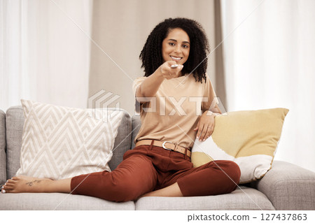 Tv, portrait and woman relax on sofa, happy and smile while channel surfing in living room at home. Black woman, remote control and watching tv on a couch, excited about weekend freedom in her house 127437863