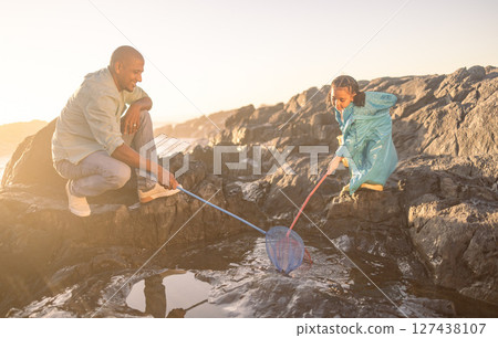 Fishing net, dad and kid, beach and ocean for learning, development and growth, summer holiday adventure and travel freedom. Happy girl child catch fish with parent in sea, nature and rock pool water Fishing net, dad and kid, beach and ocean for learning, development and growth, summer holiday adventure and travel freedom. Happy girl child catch fish with parent in sea, nature and rock pool water 127438107