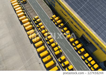 Delivery vans hub with solar panel on a roof. Fleet of yellow post vehicles. Delivery vans hub with solar panel on a roof. Fleet of yellow post vehicles. 127438244