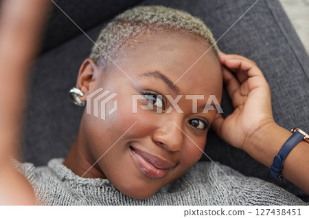 Smile, black woman on sofa and phone selfie, taking a profile picture for social media or online dating app. Relax, happy and woman laying on living room couch taking photo for self love from above. 127438451