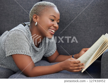 Book, relax and black woman reading on a sofa for knowledge in the living room of her house. Happy, smile and African girl enjoying a fantasy story or novel while relaxing on the couch at her home. Book, relax and black woman reading on a sofa for knowledge in the living room of her house. Happy, smile and African girl enjoying a fantasy story or novel while relaxing on the couch at her home. 127438452
