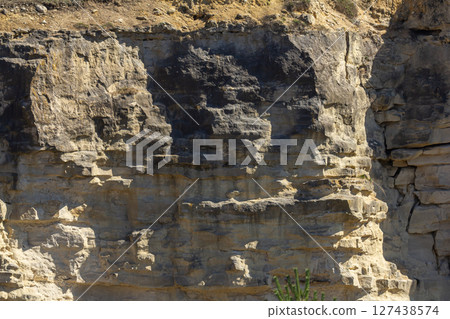 Rock formations display various geological layers in a rugged landscape during daylight showcasing natural textures and patterns found in nature Rock formations display various geological layers in a rugged landscape during daylight showcasing natural textures and patterns found in nature 127438574