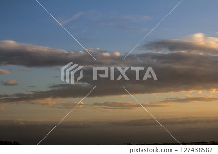 Colorful clouds drift across a serene sky at dusk over a peaceful landscape in the evening 127438582