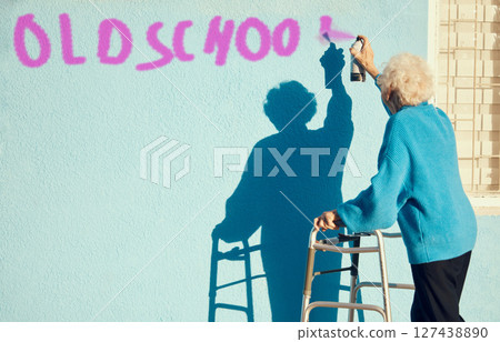 Senior woman, graffiti and wall with spray paint for street art in city, town or metro in retirement. Elderly rebel, painting or pop art in urban outdoor with vandalism, spray or painting in sunshine 127438890