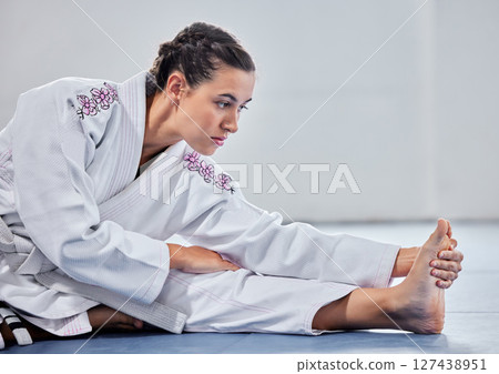 Martial arts, fitness and stretching with woman in karate school for training, sports and fight performance. Strong, focus and warm up with girl student in dojo studio for taekwondo, workout or club 127438951