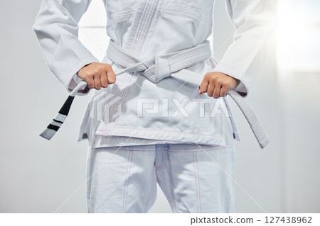 karate belt, martial arts and woman ready for fight battle, white dojo training or fitness challenge workout. Warrior motivation, taekwondo and hands of girl learning self defense for safety security 127438962