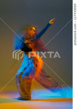 Jazz-funk dancer in vibrant motion blur, striking a bold pose with flowing lights and urban energy in a colorful studio setting. Jazz-funk dancer in vibrant motion blur, striking a bold pose with flowing lights and urban energy in a colorful studio setting. 127439084