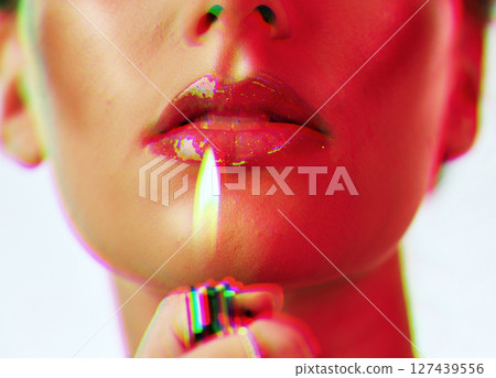 Makeup, beauty and woman with mouth lighter flame for an edgy, gen z and futuristic cosmetic campaign. Neon hologram face effect on shiny lip gloss cosmetics model zoom in white studio. 127439556