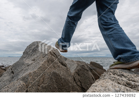 The feet of a person climbing over a rocky area 127439892