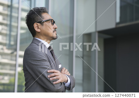 一位 50 多歲的商人,雙臂交叉,側面肖像 一位 50 多歲的商人,雙臂交叉,側面肖像 127440071