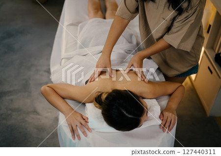 Top view of a woman receiving a professional back massage in a relaxing spa setting. Wellness concept 127440311