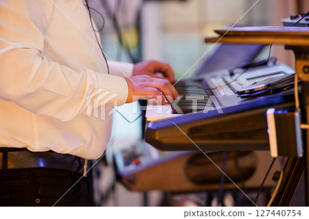 Live Music Performance Featuring a Keyboardist in a Formal Setting with musical Equipment, Stage Lighting, and White Shirt Live Music Performance Featuring a Keyboardist in a Formal Setting with musical Equipment, Stage Lighting, and White Shirt 127440754