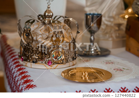 Eastern Orthodox Coronation Ceremony: Golden Crown, Chalice, and Paten on Red Textile Altar, Religious Ritual, Silverware, Sacred Objects 127440822