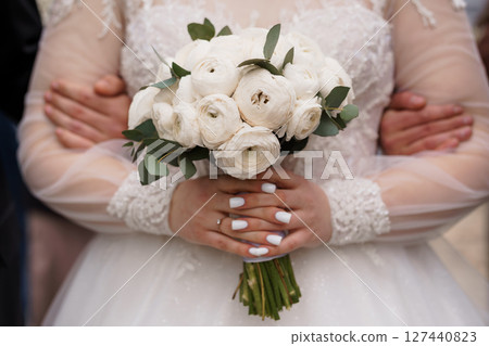 Elegant White Wedding Bouquet Held by Bride with Long Sleeves, Close-Up View. Romance, Classic Floral Arrangement, Celebration Theme. Elegant White Wedding Bouquet Held by Bride with Long Sleeves, Close-Up View. Romance, Classic Floral Arrangement, Celebration Theme. 127440823